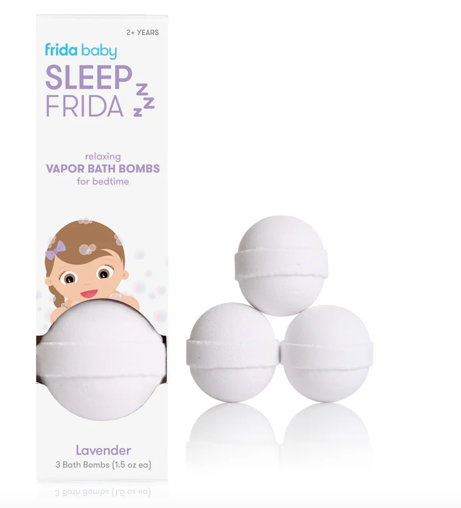 Frida Baby newborn gift set including Baby Basics Kit, grooming tools, Soft Sink Baby Bath, and Sleep Vapor Bath Bombs arranged on a neutral linen surface at Cuddles and Carriages in Evans, GA