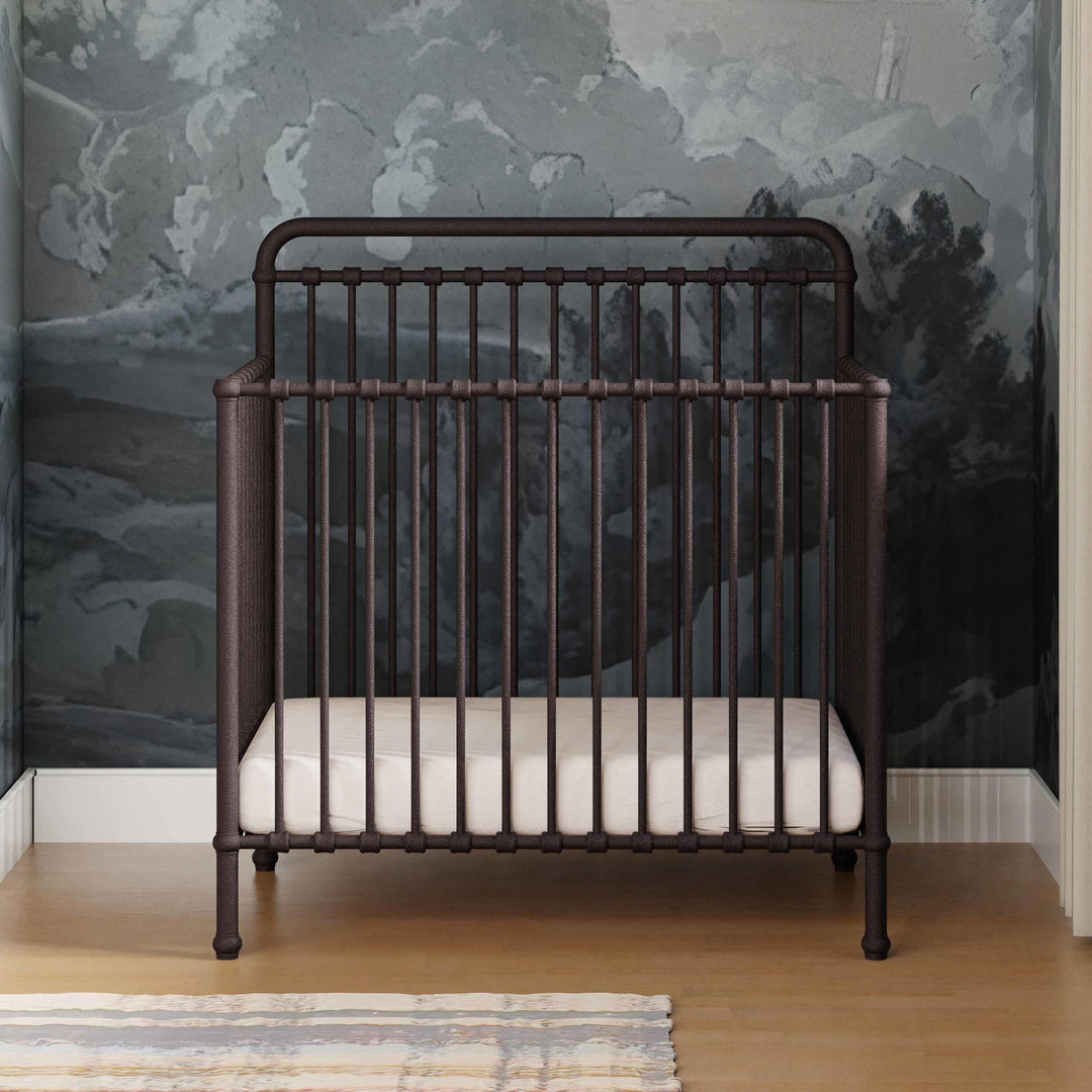Namesake Winston 4-in-1 convertible mini crib styled in a small-space nursery