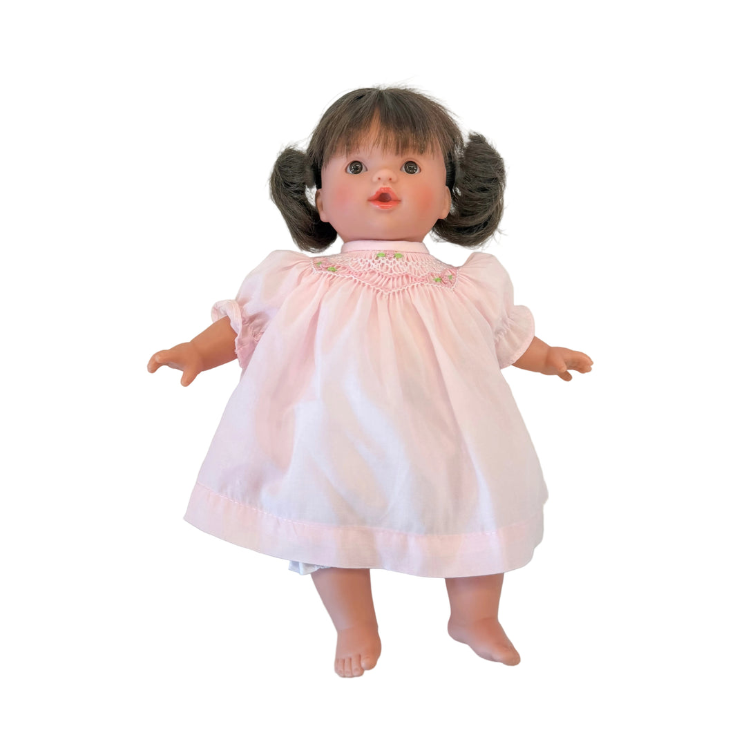 Vintage doll with a pink dress on a white marble surface