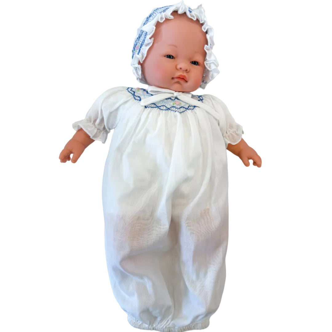 Baby doll wearing a white outfit with blue trim on a marble surface